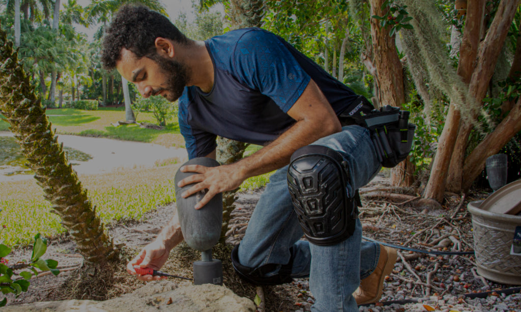 Electrician, gardener, or maintenance worker repairing an outdoor garden light. He is using Gel filled kneepads with heavy-duty shell caps to keep his knees safe and free of pain while he kneels for extended periods of time to work. 