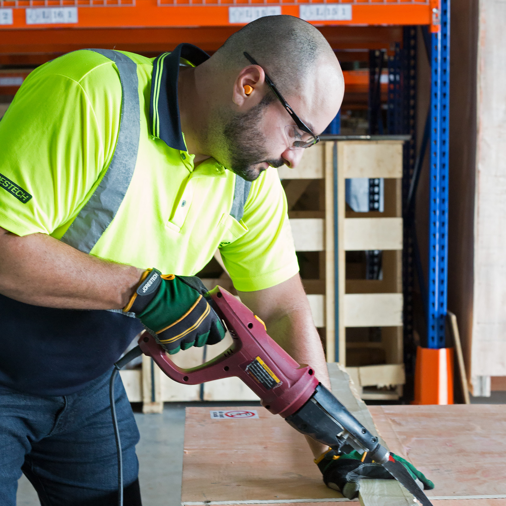 A worker wearing JORESTECH ear plugs for loud noise cancelation while operating a power tool to cut wood.