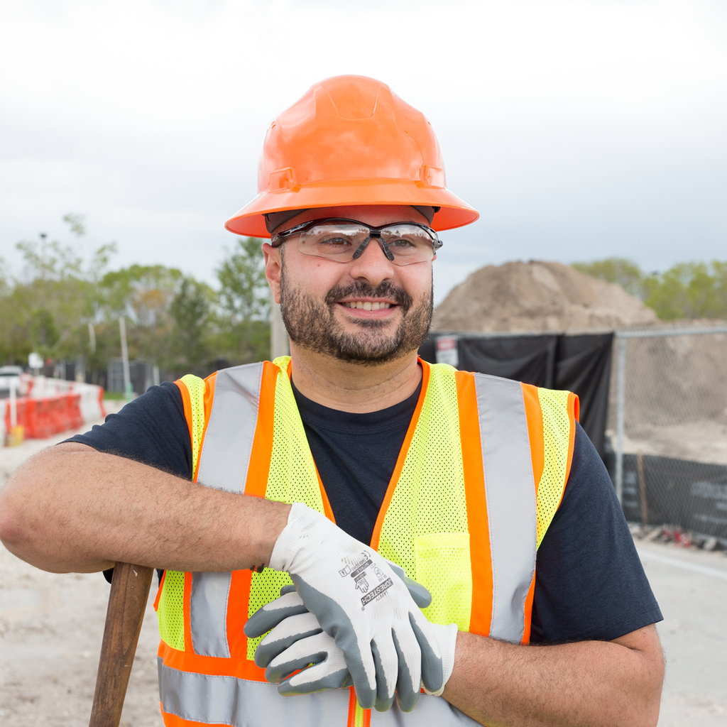 A worker wearing PPE in a road construction setting, he is also wearing the orange Jorestech full brim hard hat with 4 point suspension