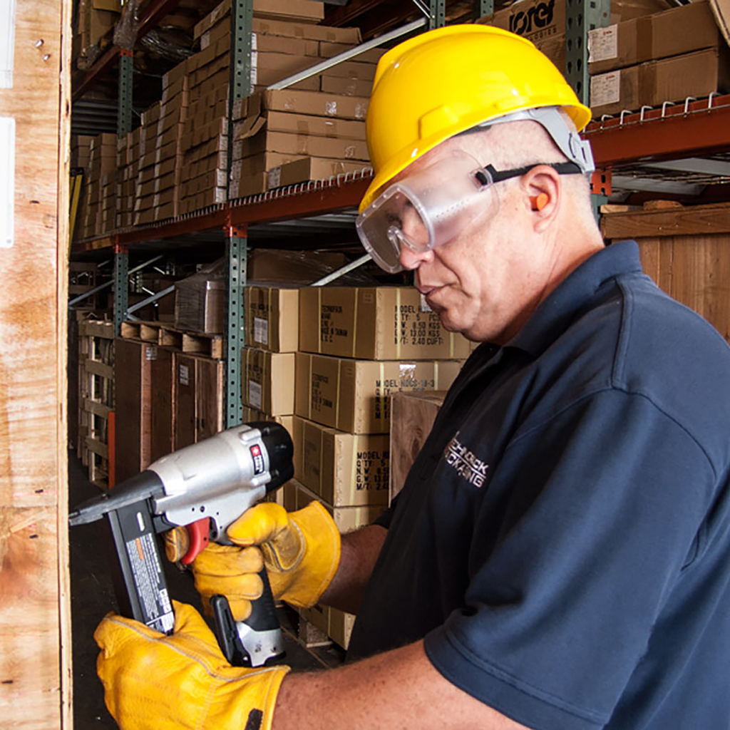 Image of a worker wearing JORESTECH Safety Goggles for Impact Protection while drilling a crate in a warehouse setting