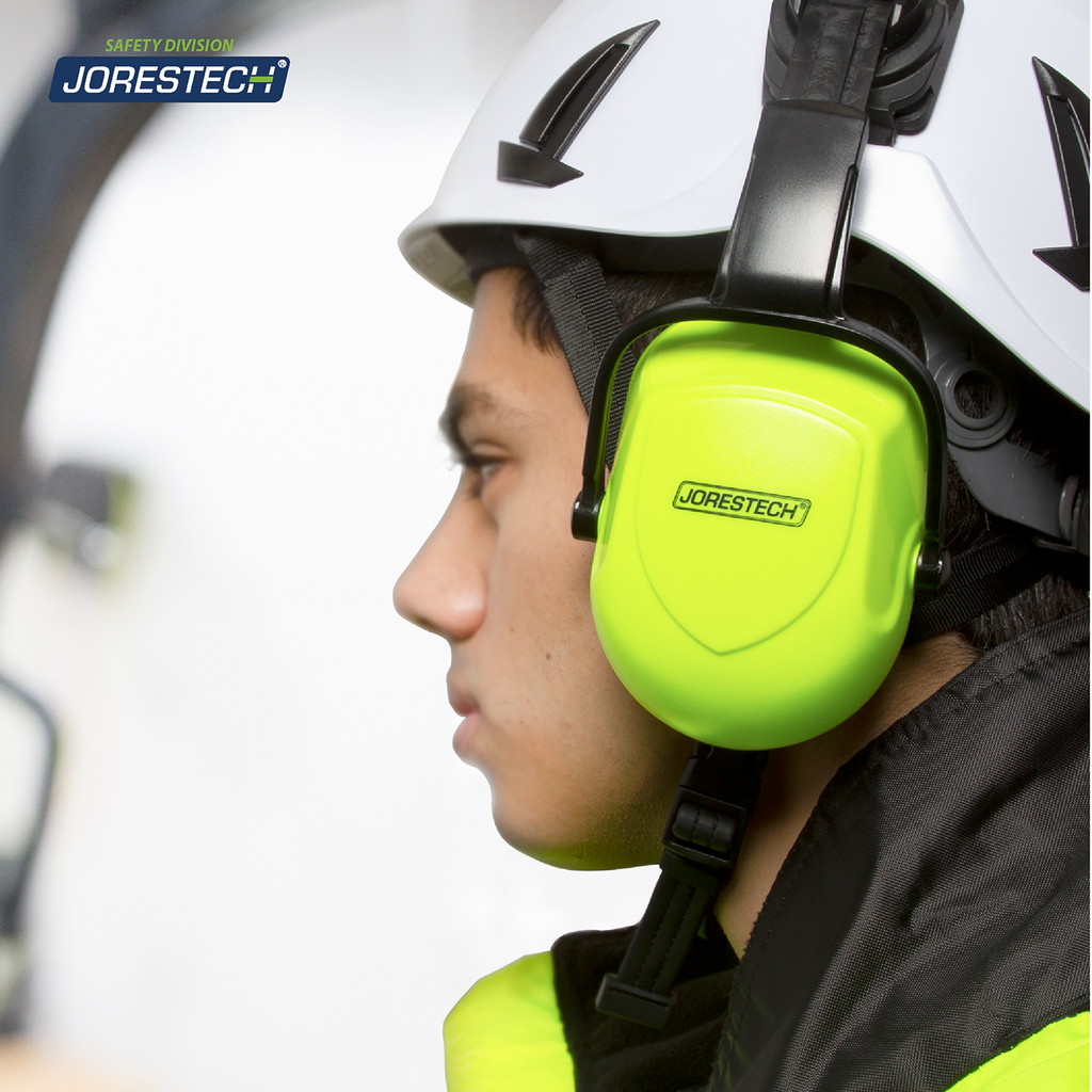 A worker wearing a white ventilated hard hat with mounted lime earmuffs in a construction setting